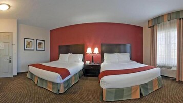 A hotel room with two beds, a nightstand with a lamp, and a window with curtains.