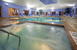 An indoor swimming pool with multiple lanes, lounge chairs, and a clear water surface.