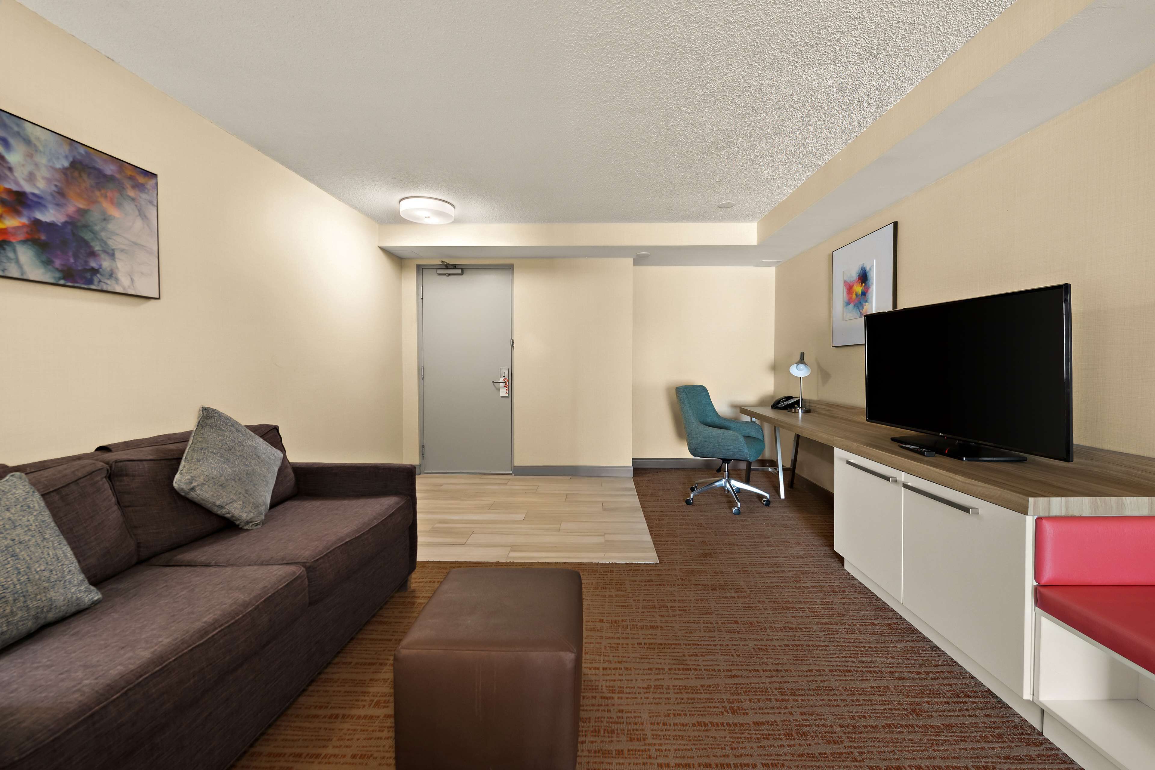 Una sala de estar moderna con un sofá, un reposapiés y un televisor de pantalla plana sobre un mueble de madera.