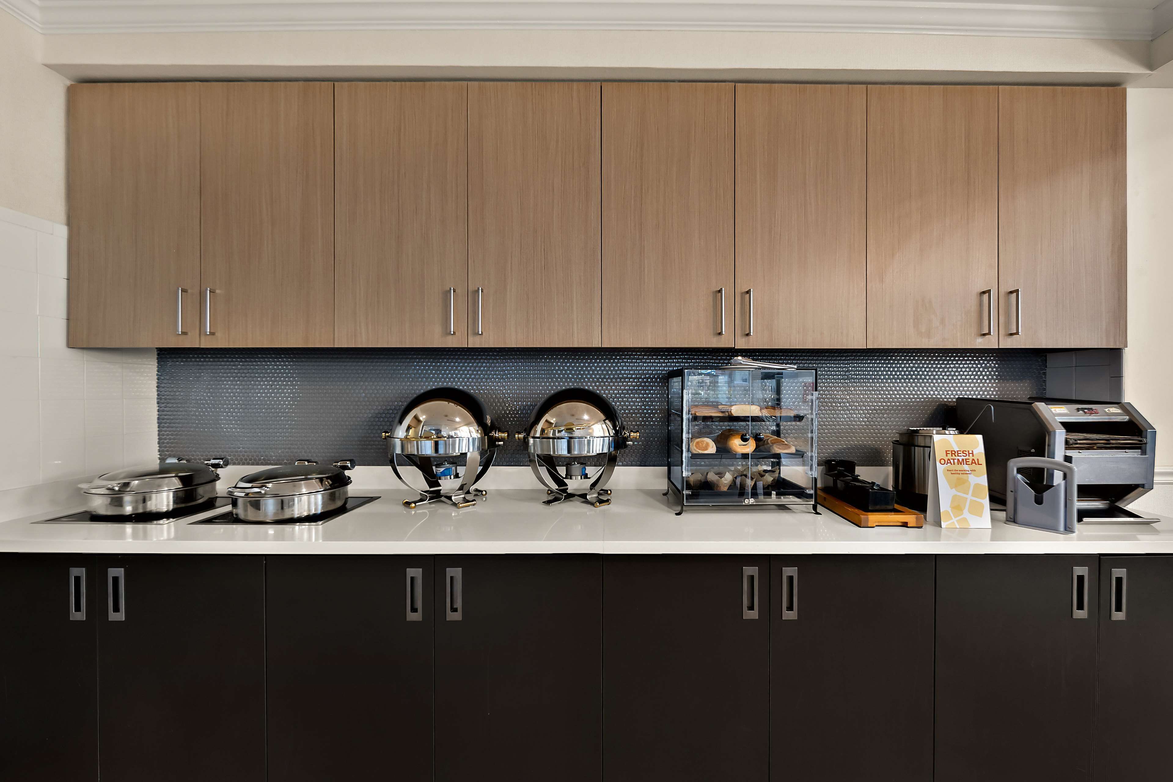 Una cocina moderna con armarios de madera, protector contra salpicaduras negro y electrodomésticos de acero inoxidable.