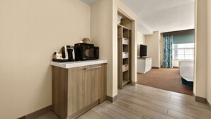 A hotel room with a kitchenette, a bed, a TV, and a bathroom visible through an open door. - Hilton Garden Inn Williamsburg (Williamsburg)