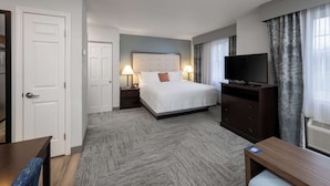 A hotel room with a bed, two bedside tables with lamps, a TV, a desk, and a chair. - Homewood Suites by Hilton Boston / Andover (Andover)