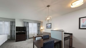 A hotel room with a bed, a desk with a chair, a television, a lamp, a picture on the wall, and a small kitchenette. - Homewood Suites by Hilton Boston / Andover (Andover)