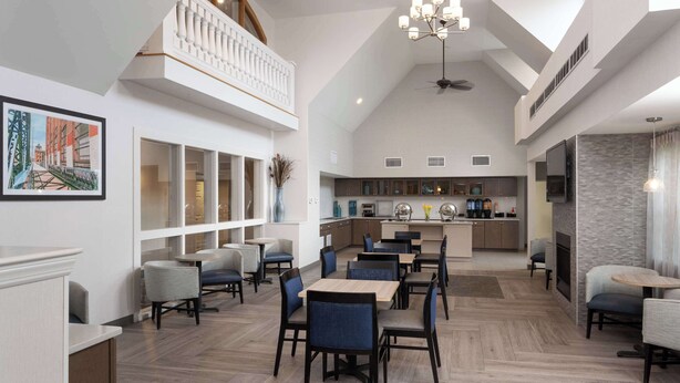 A spacious dining area with high ceilings, a mezzanine level, and a modern kitchen in the background. - Homewood Suites by Hilton Boston / Andover (Andover)