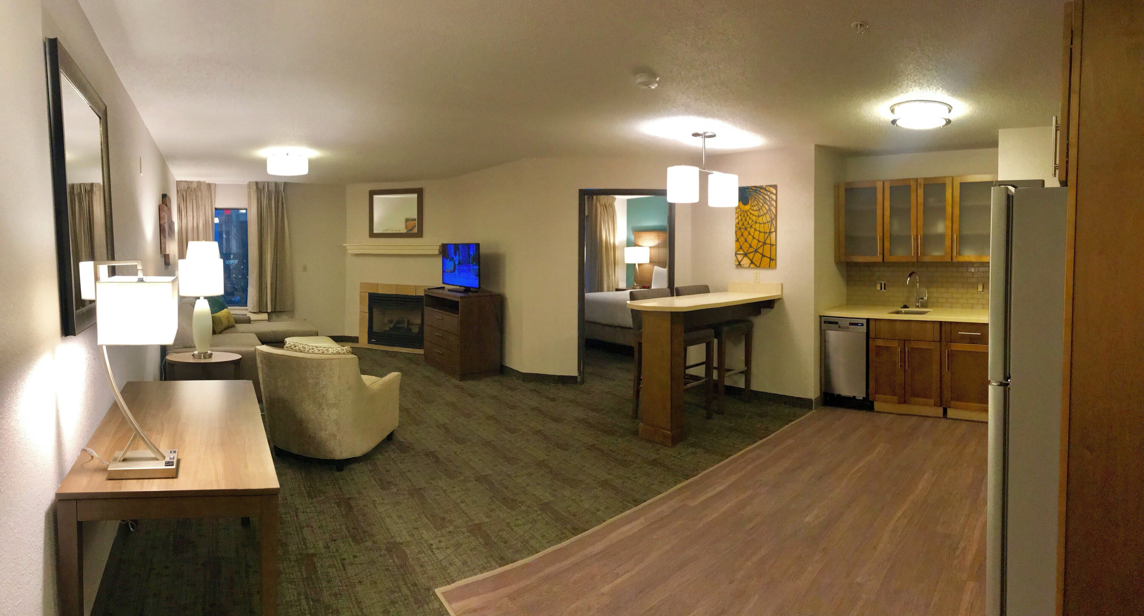 Quarto de hotel com sala de estar, mesa de jantar, cozinha e lareira.