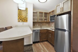A compact kitchen with wooden cabinets, a stainless steel refrigerator, and a dishwasher. - Staybridge Suites Columbia by IHG (Columbia)
