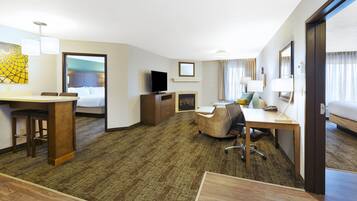 Une chambre d’hôtel équipée d’un lit, d’un bureau, d’une chaise, d’une télévision et d’un petit coin salon.