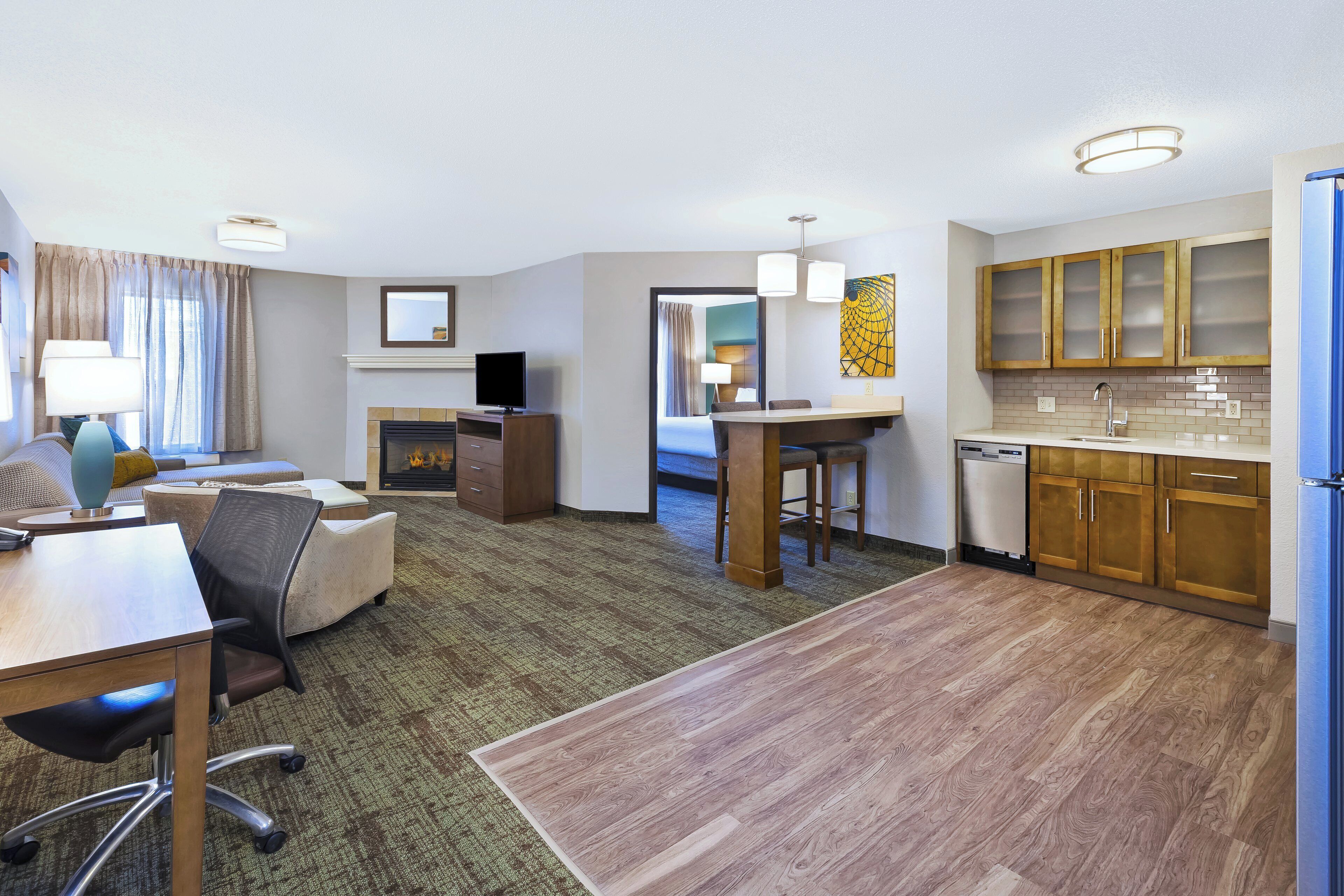 Habitación de hotel con comedor, kitchenette y una cama.