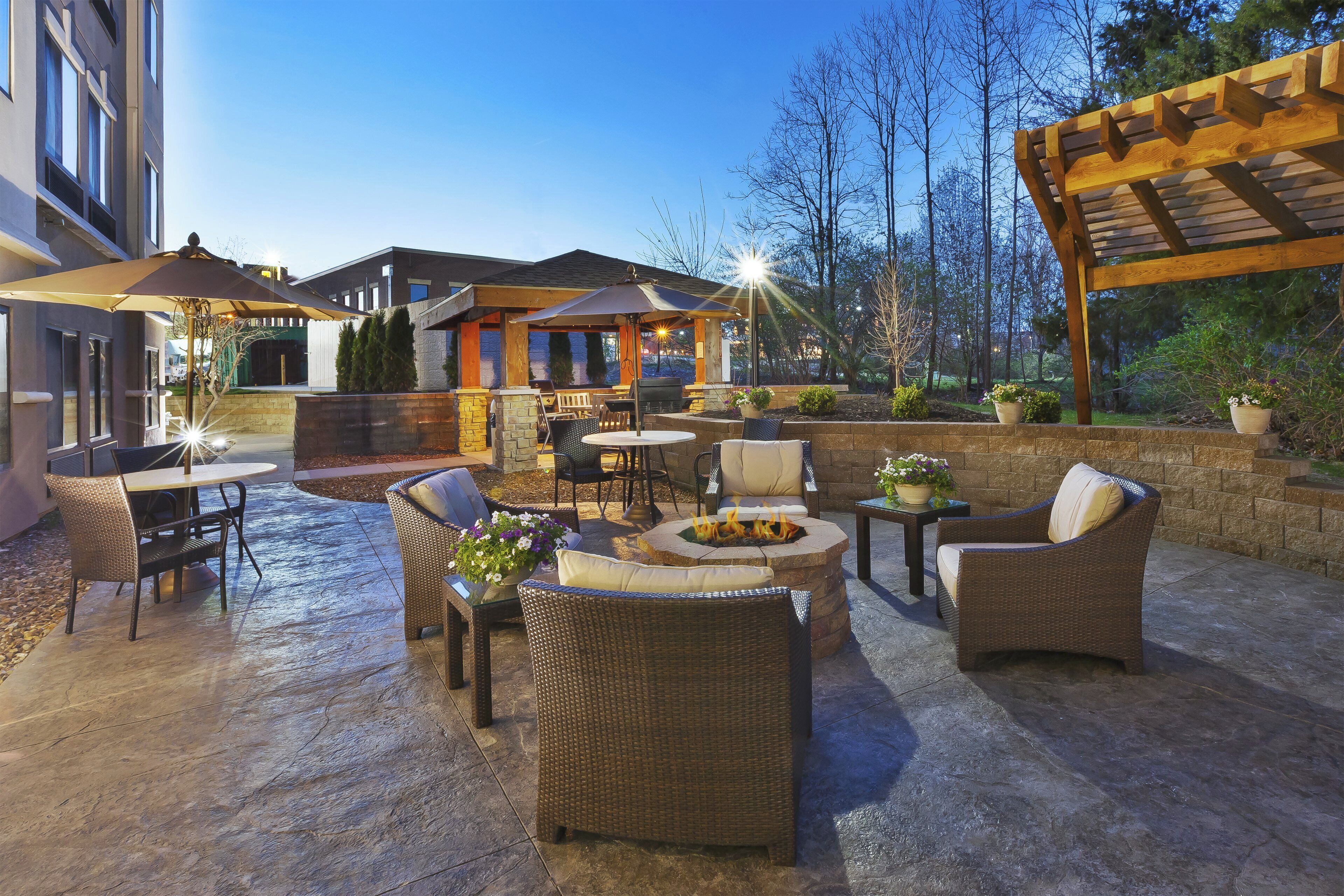 An outdoor patio area with wicker furniture, a fire pit, and a covered seating area.