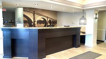 A reception area with a large counter, a wall-mounted screen displaying a bridge, and a modern light fixture.