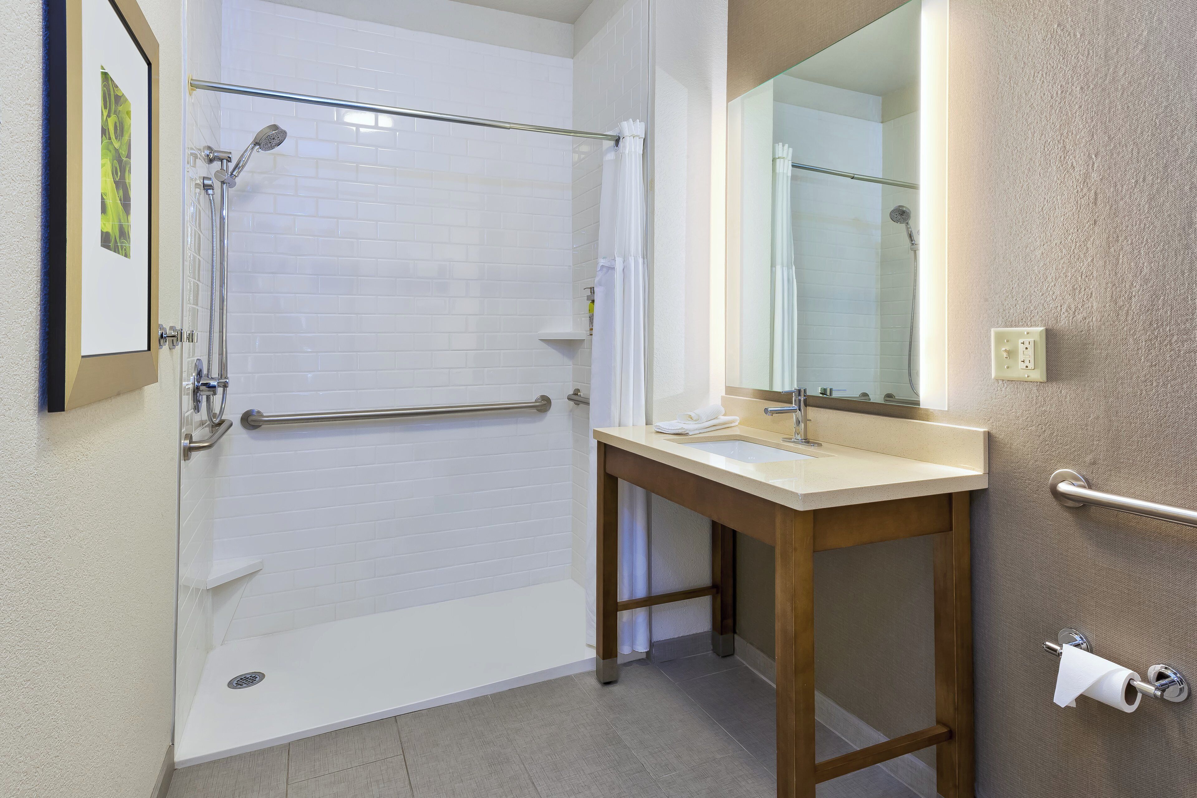 A bathroom with a shower, toilet, sink, and mirror.