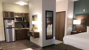 Une chambre d’hôtel comprenant un lit, un bureau, une kitchenette et une salle de bain.