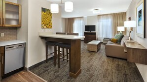 Une chambre d’hôtel moderne équipée d’un coin cuisine, d’une table à manger, d’un canapé et d’un téléviseur.