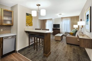A modern hotel room with a kitchen area, a dining table, a sofa, and a TV. - Staybridge Suites Columbia by IHG (Columbia)