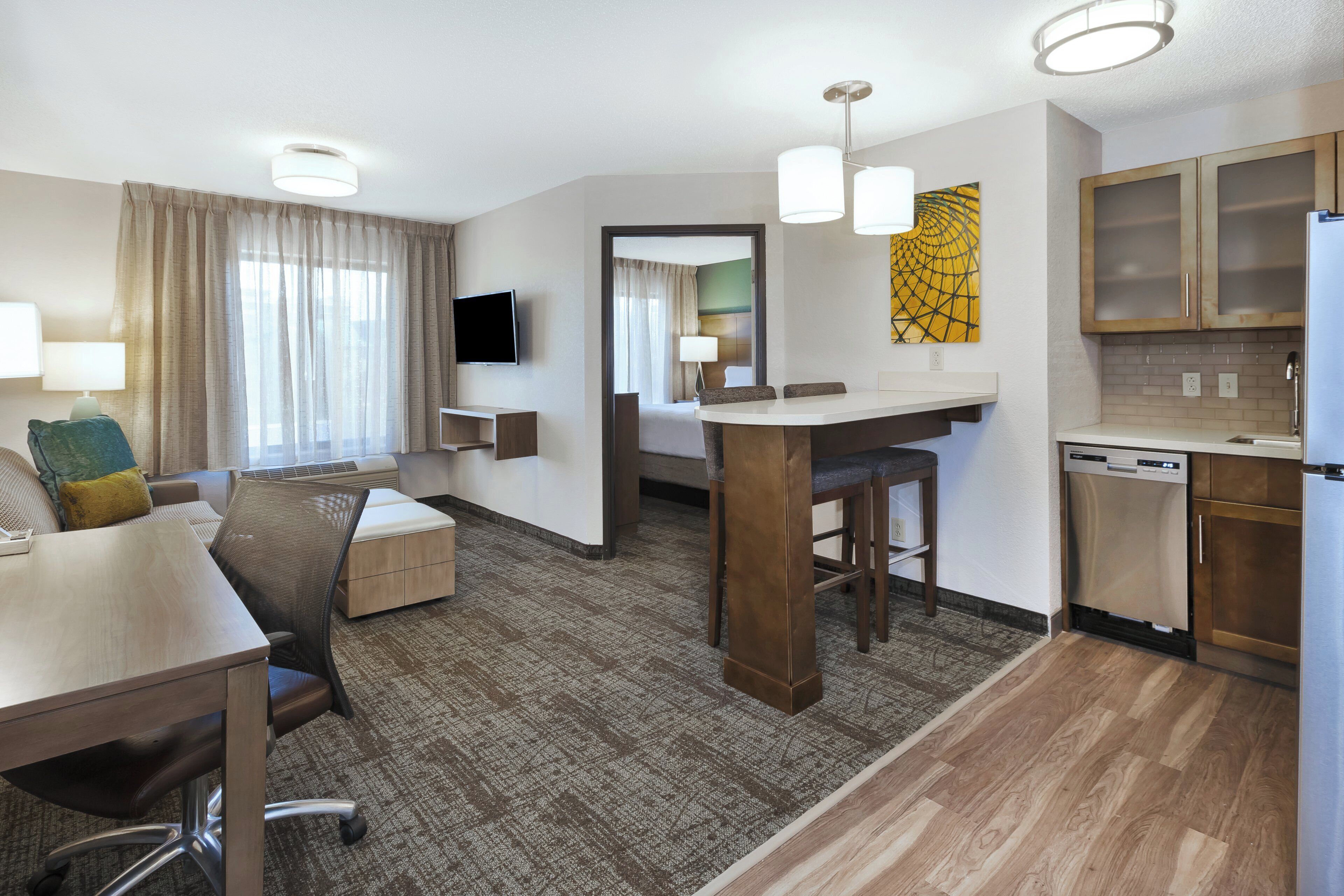 Habitación de hotel con comedor, kitchenette y televisor.
