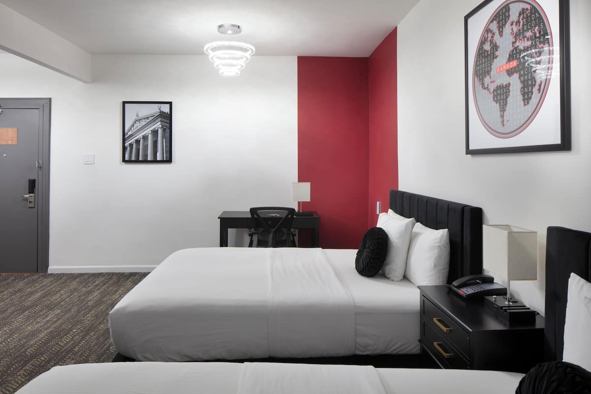A hotel room with a large bed, a desk, a chair, a nightstand, and a world map on the wall.