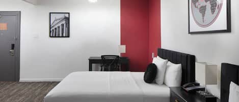 Habitación de hotel con una cama grande, un escritorio, una silla, una mesita de noche y un mapa del mundo en la pared.