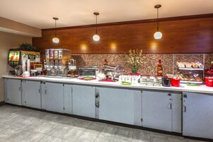 Un mostrador de desayuno tipo buffet con diversas opciones de alimentos, una máquina de café y un microondas.