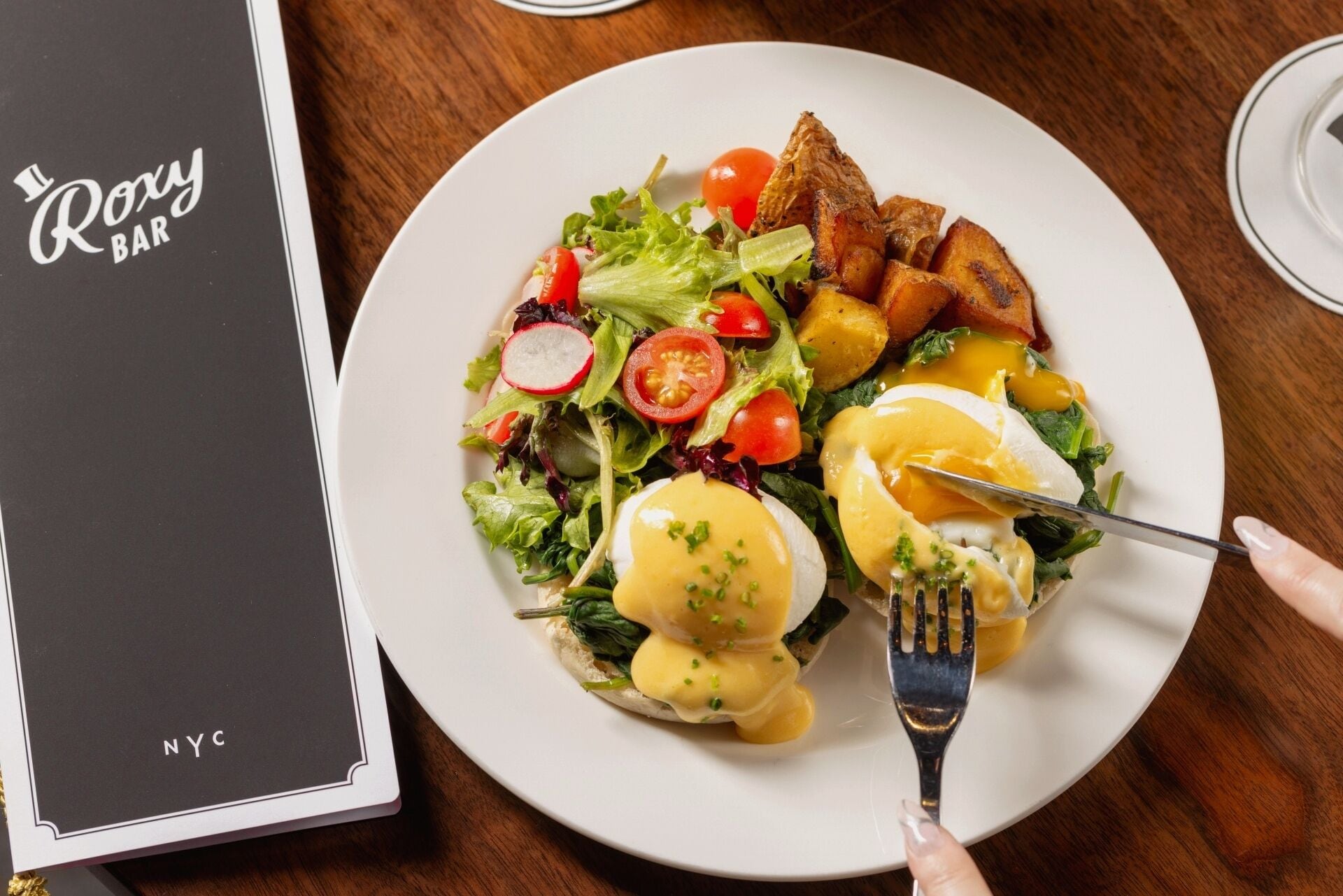 En tallrik med mat, bestående av en sallad, ägg och rostat bröd, samt en meny med titeln ”Roxy Bar” där det står ”NYC” på.