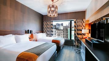 A hotel room with two beds, a TV, a desk, and a view of the city.