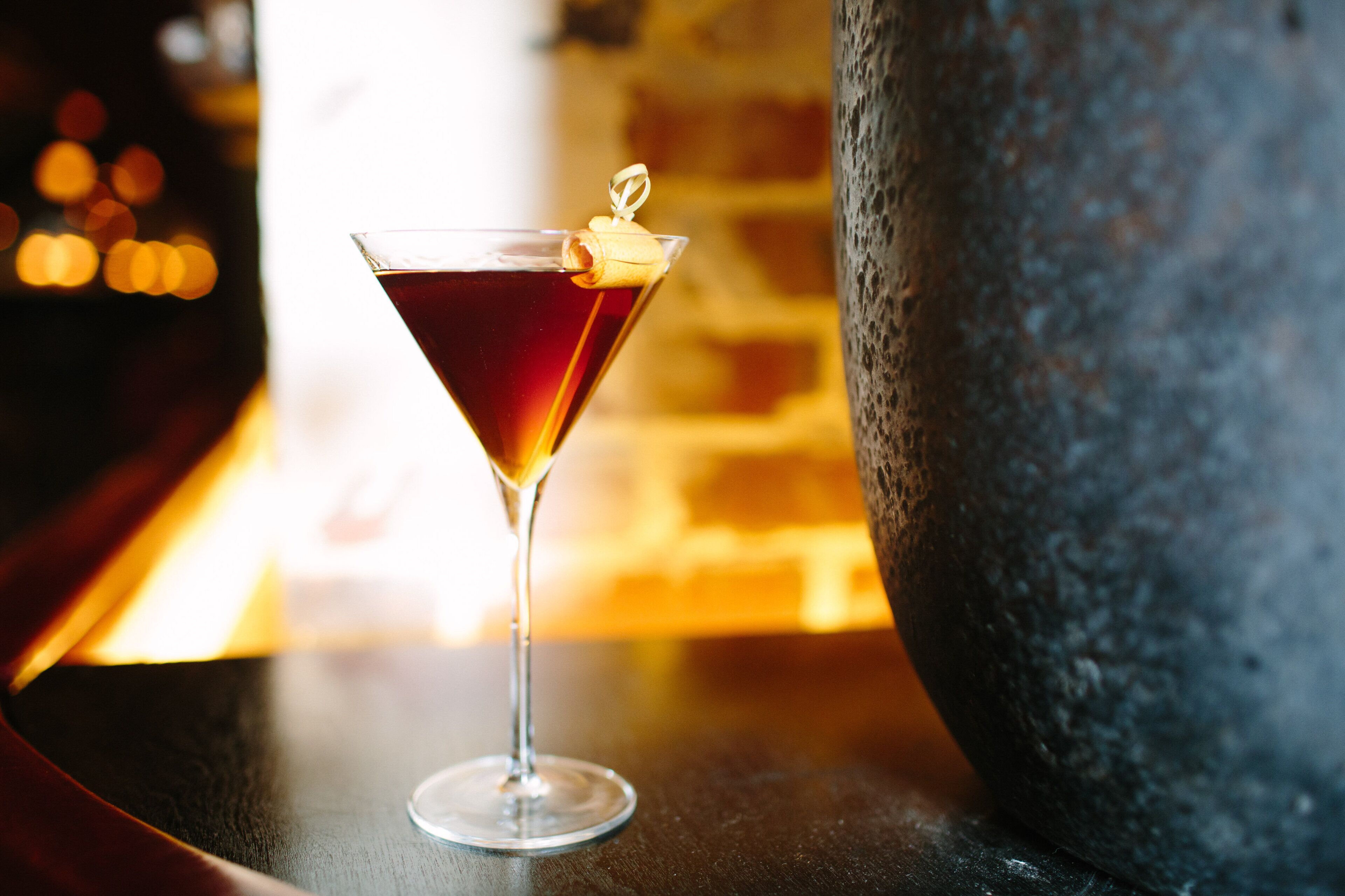 Una copa de martini con una rodaja de limón sobre una barra.