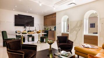 A modern living room with a sofa, armchairs, a coffee table, and a dining area with a table set for a meal.