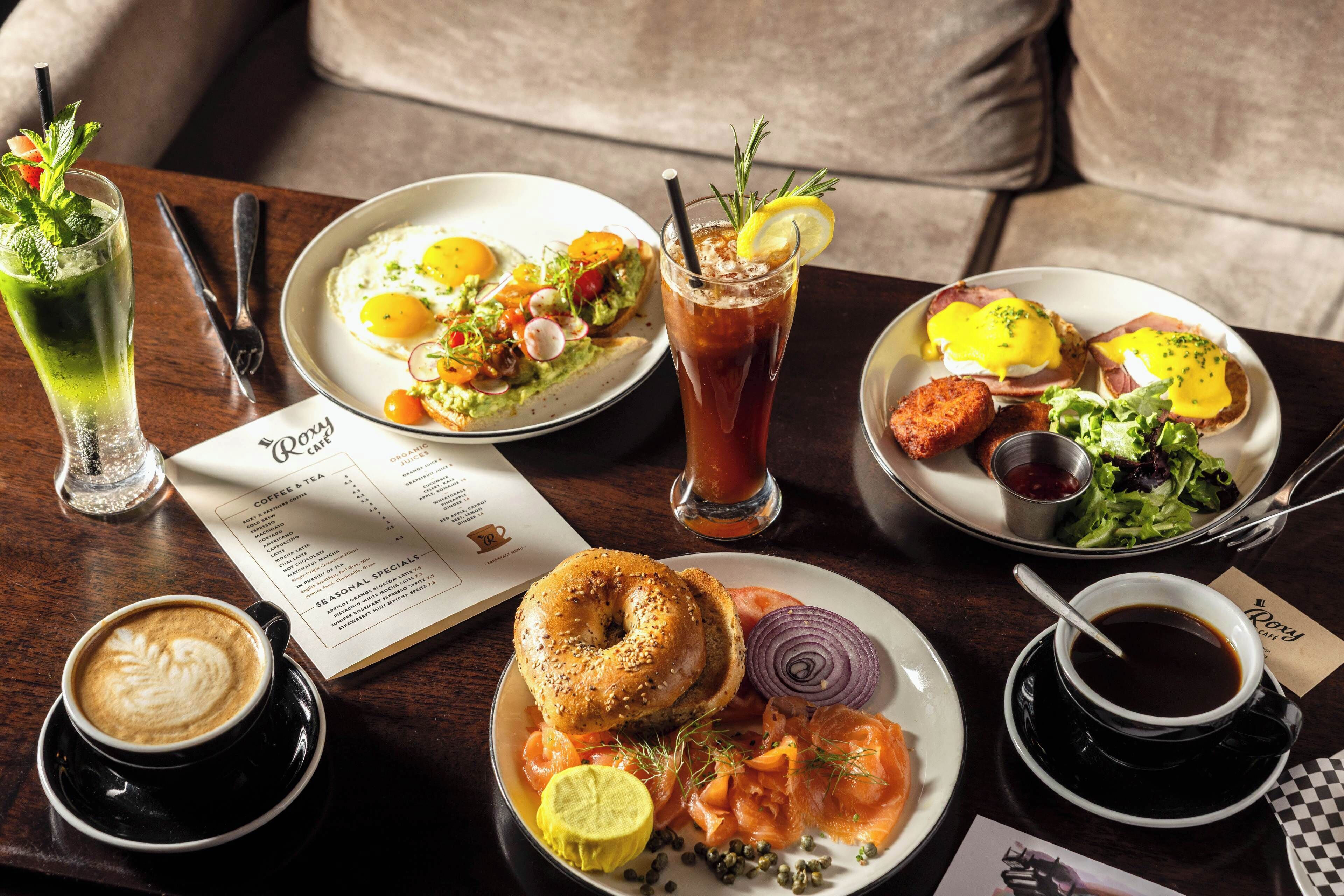 A table with breakfast items including eggs, avocado toast, smoked salmon, and coffee.