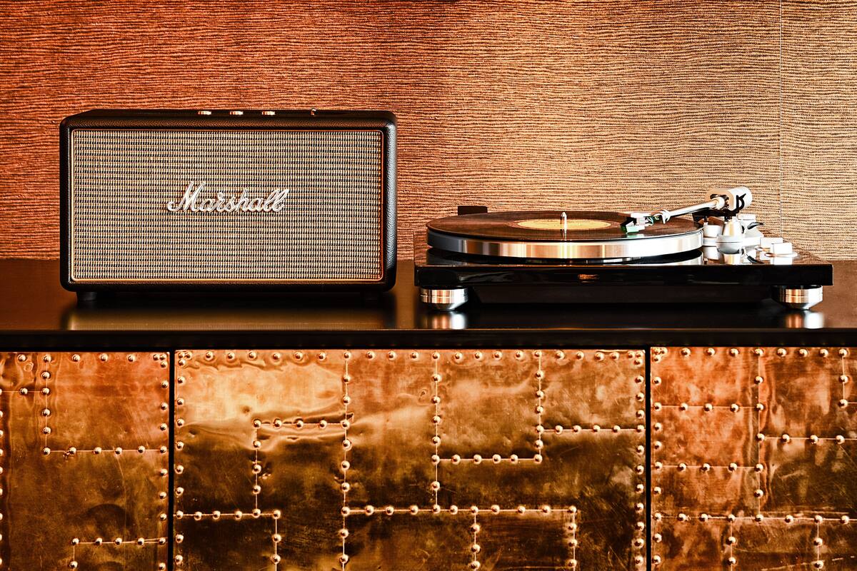 A turntable with a Marshall amplifier on a wooden surface with a copper-toned cabinet.