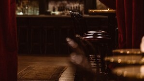 A bar area with a wooden floor, a bar counter, and a person standing near the counter. - Roxy Hotel New York (New York)