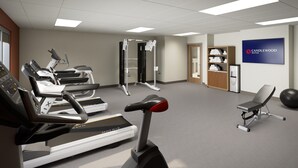 Un gimnasio con cintas de correr, una máquina de pesas y una silla.