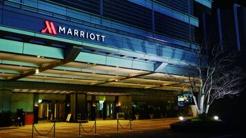 A Marriott hotel entrance with a modern glass facade, a visible entrance, and a security barrier.