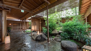 Un patio japonés tradicional con suelo de piedra, plantas de bambú y un farol.