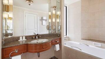 A modern bathroom with a double sink vanity, a large mirror, a bathtub, and a shower area.