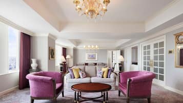 A spacious living room with a large chandelier, a sofa set, and two armchairs.