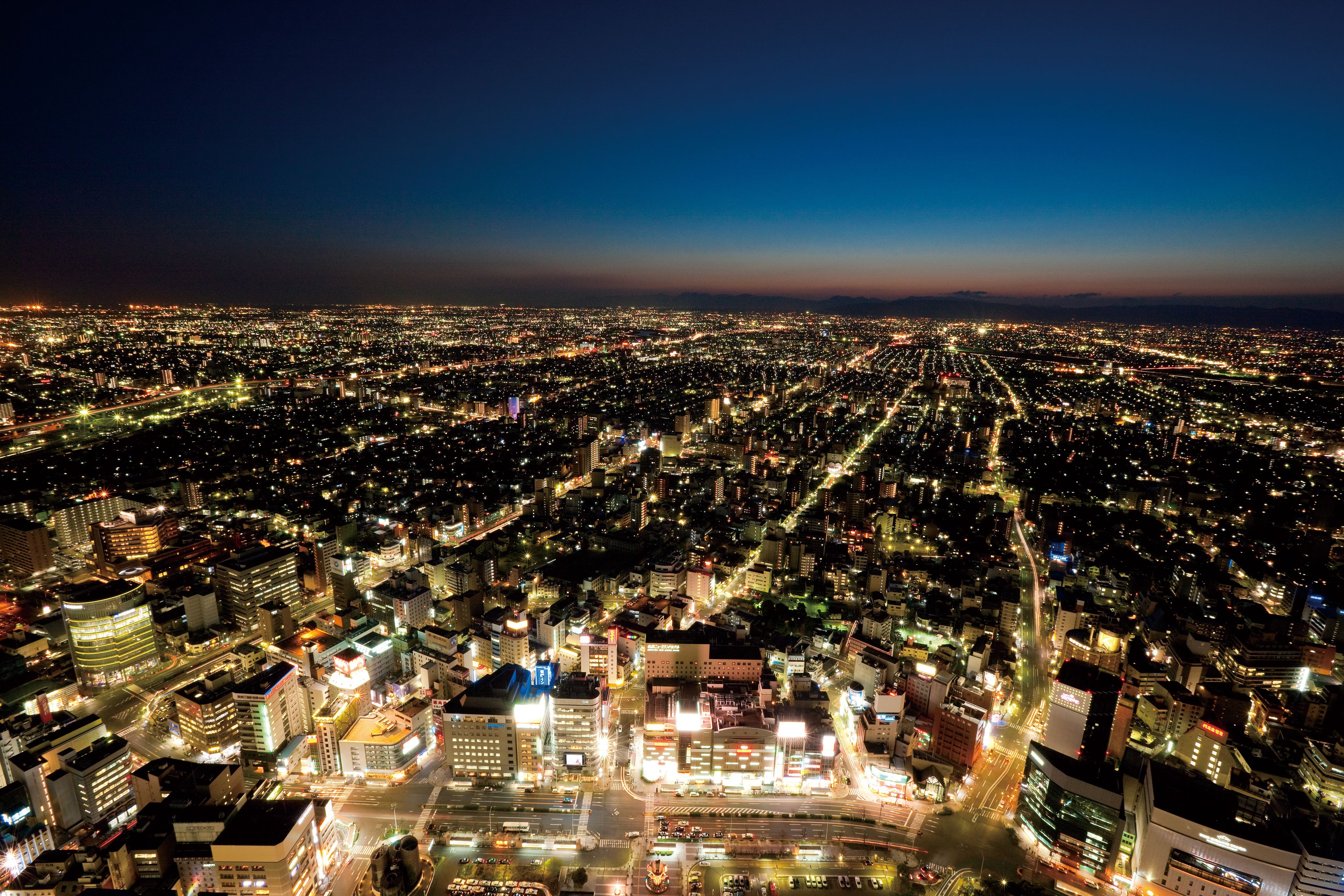 A nighttime cityscape with a dense urban layout, illuminated streets, and a variety of building structures.