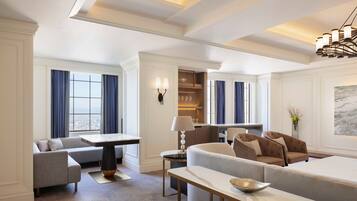 A modern hotel room with a living area featuring a sofa, a dining table, and a kitchen area.