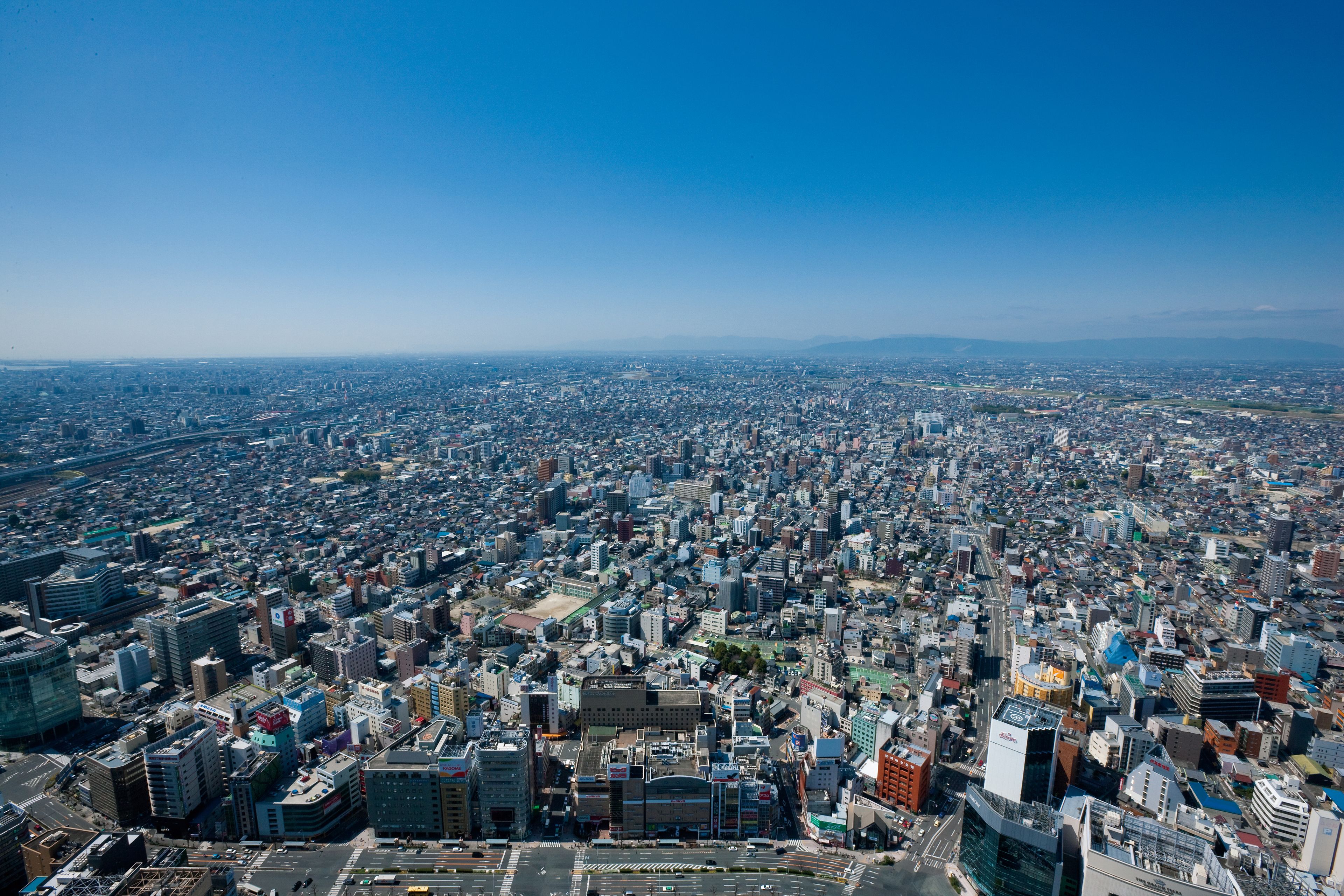 A panoramic view of a densely populated urban area with numerous high-rise buildings and a clear blue sky.