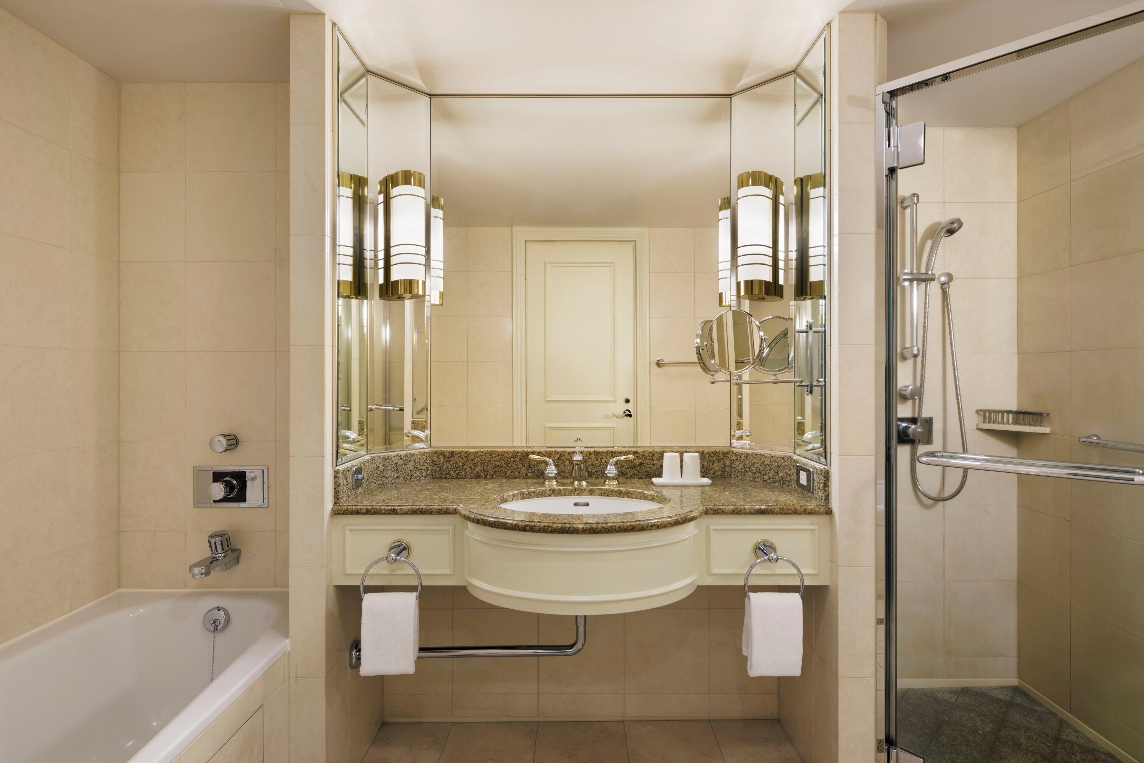 Un baño moderno con lavamanos doble, bañera, ducha con mampara de vidrio y un espejo grande.