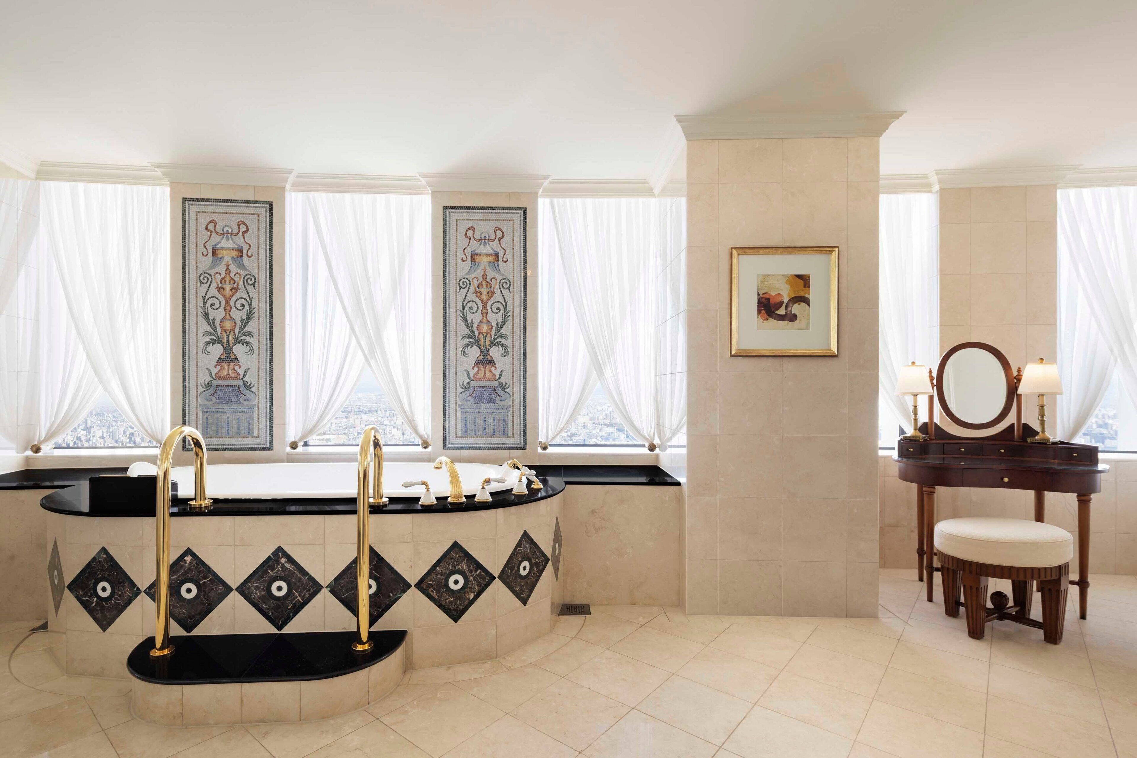 A bathroom with a freestanding bathtub, a vanity with a mirror, and decorative tiles.