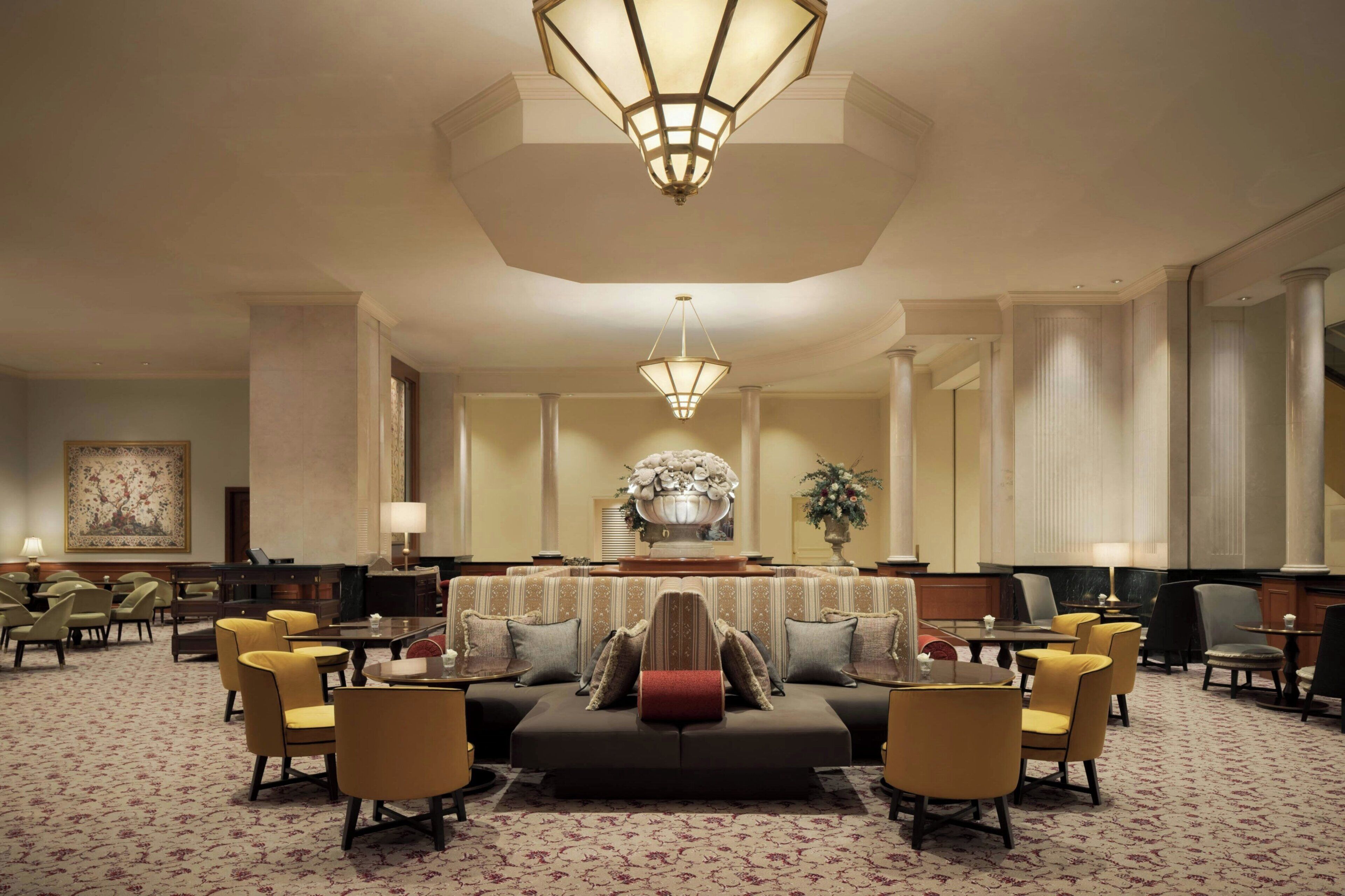 A spacious lobby with a central seating area, a reception desk, and a large decorative mirror.