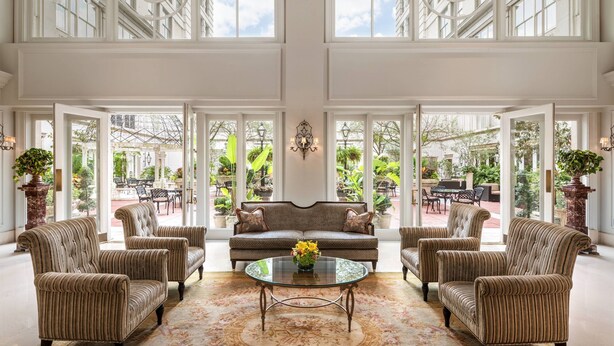 A spacious room with a large window, a sofa, armchairs, and a coffee table.