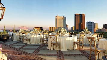 An outdoor dining area with tables set for a meal, featuring a city skyline in the background.