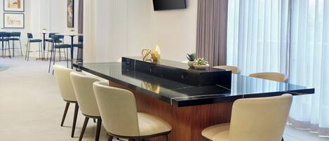 Una cocina moderna con una isla central, taburetes de bar, iluminación colgante y vistas al comedor.