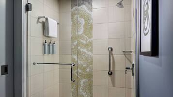 A modern shower area with a glass door, a towel rack, and a vertical mosaic panel.