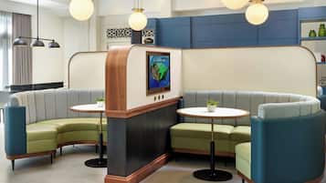 A modern lounge area with a curved sofa, two small round tables, and pendant lighting.