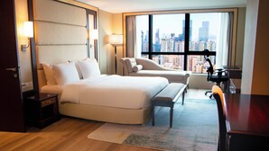 A hotel room with a large bed, a chair, a desk, and a view of a cityscape through a large window. - Holiday Inn Shenzhen Donghua by IHG (Shenzhen)
