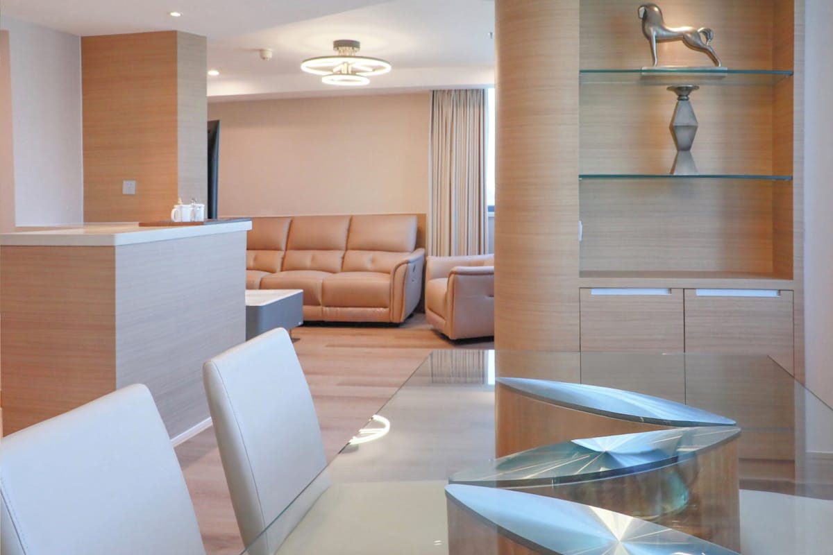 A modern hotel lobby with a reception desk, leather seating, and a glass coffee table.