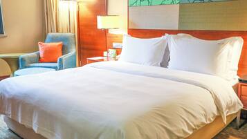 A hotel room with a large bed, a chair, a nightstand, and a lamp.