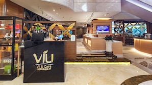 A modern hotel lobby with a prominent black reception desk labeled "VIU Café," a digital screen, and a staircase leading to an upper level. - Holiday Inn Shenzhen Donghua by IHG (Shenzhen)