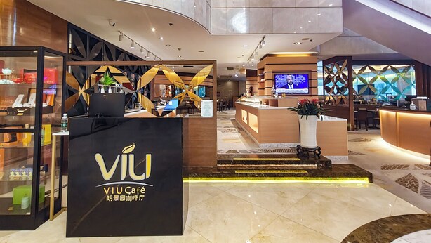 A modern hotel lobby with a prominent black reception desk labeled "VIU Café," a digital screen, and a staircase leading to an upper level. - Holiday Inn Shenzhen Donghua by IHG (Shenzhen)
